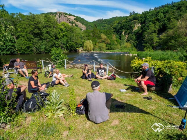 Briefing zum ersten Packrafting Erlebnistag Nahe im Jahr 2020 am Campingplatz mit Blick auf die Nahe, die Teilnehmer*innen sitzen mit Abstand auf der Wiese