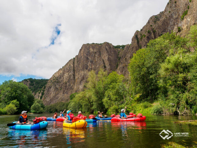 Eine Gruppe mit bunten Packrafts auf der Nahe bestaunt die Natur am Rotenfels