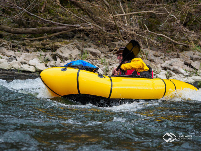 Eine Person mit Hut in einem gelben Packraft geht in die Welle der Nahe