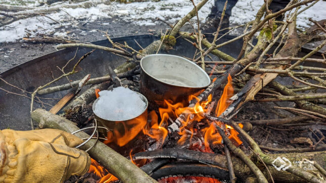 Schneeschmelzen im Topf im Lagerfeuer