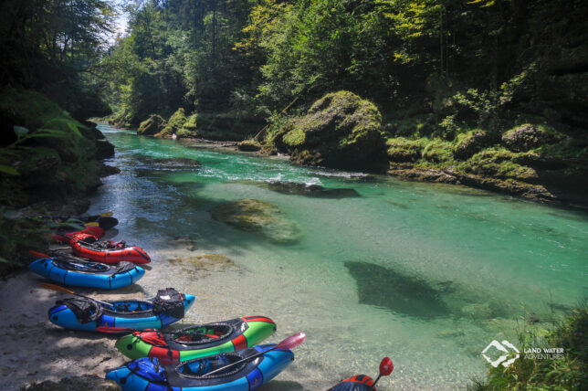 Ruhig liegen eine Handvoll bunter Packrafts am Ufer der türkisfarbenen Salza