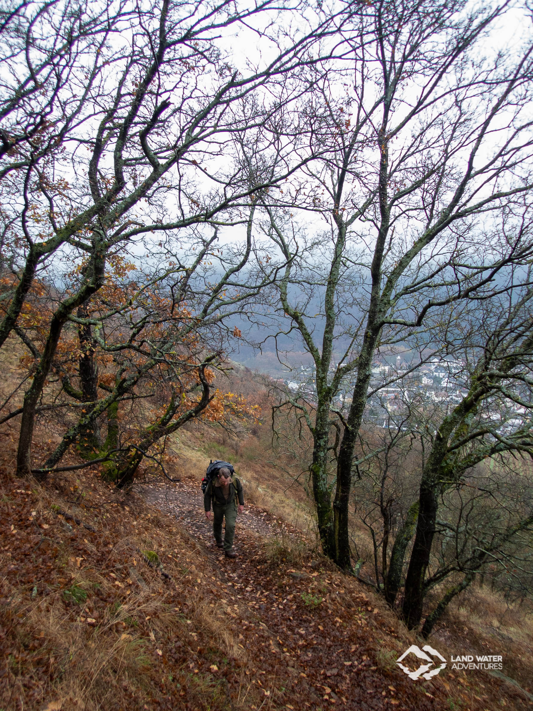 Ein Mann mit großem Rucksack wandert den schmalen Trail den Rotenfels hinauf