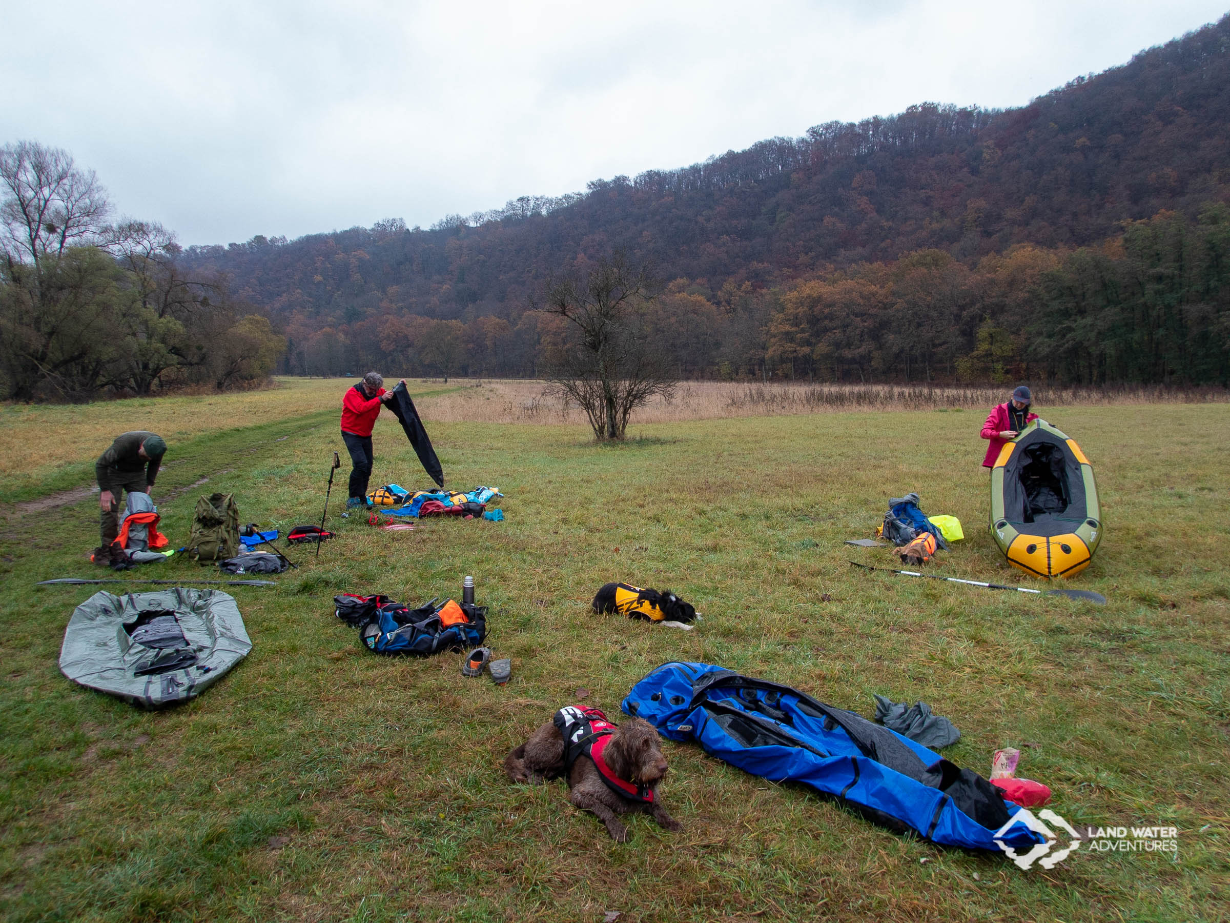 Landschaft an der Nahe, mittendrin werden bunte Packrafts aufgebaut