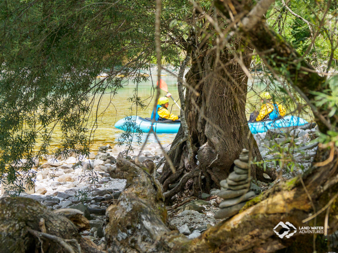 Landschaft der Soca, im Hintergrund unscharf zwei Packrafter