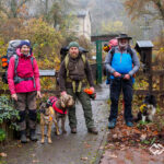 Drei Packrafter mit Hunden und großen Rucksäcken