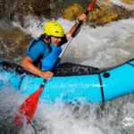 Ein blaues Packraft in der Welle