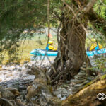 Behind the scences Landschaft der Soca, im Hintergrund unscharf zwei Packrafter