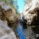Feeling so small... Ein Packrafter im blauen Boot paddelt zwischen großen Felsblöcken in Slowenien